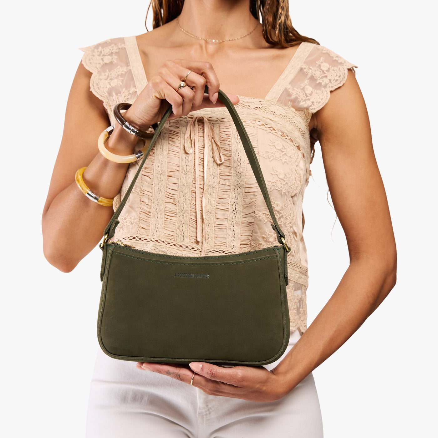 Verdant*Small | Model carrying petite bean shaped shoulder bag with a zipper closure