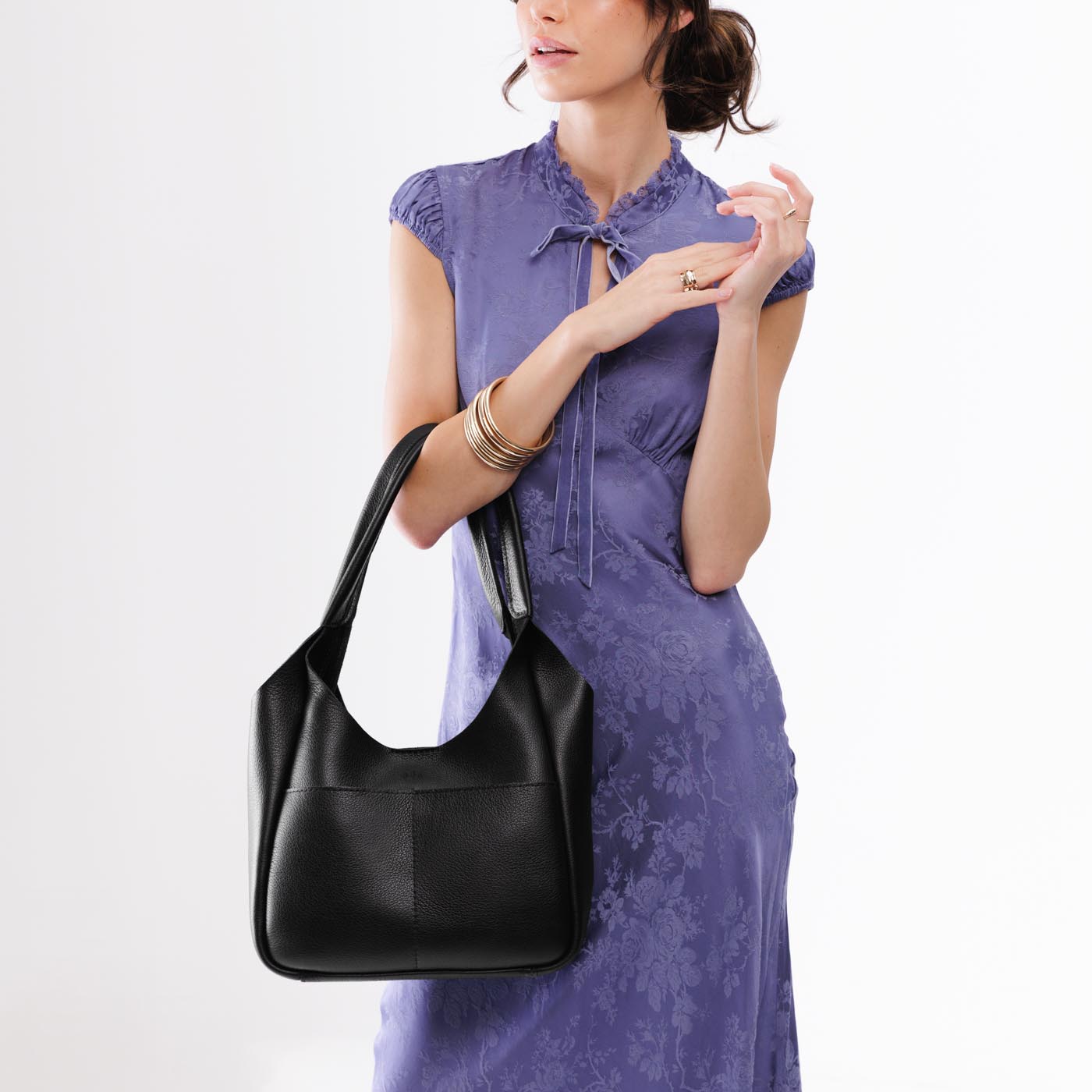 Pebbled--Black*Large | A model holding a u-shaped, flat-bottomed leather shoulder bag with two outside pockets
