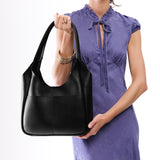 Pebbled--Black Large | A model holding a u-shaped, flat-bottomed leather shoulder bag with two outside pockets