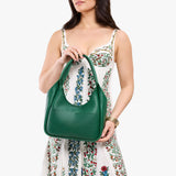 Bacalar Medium | Model holding U-shaped, flat-bottomed leather shoulder bag with two outside pockets