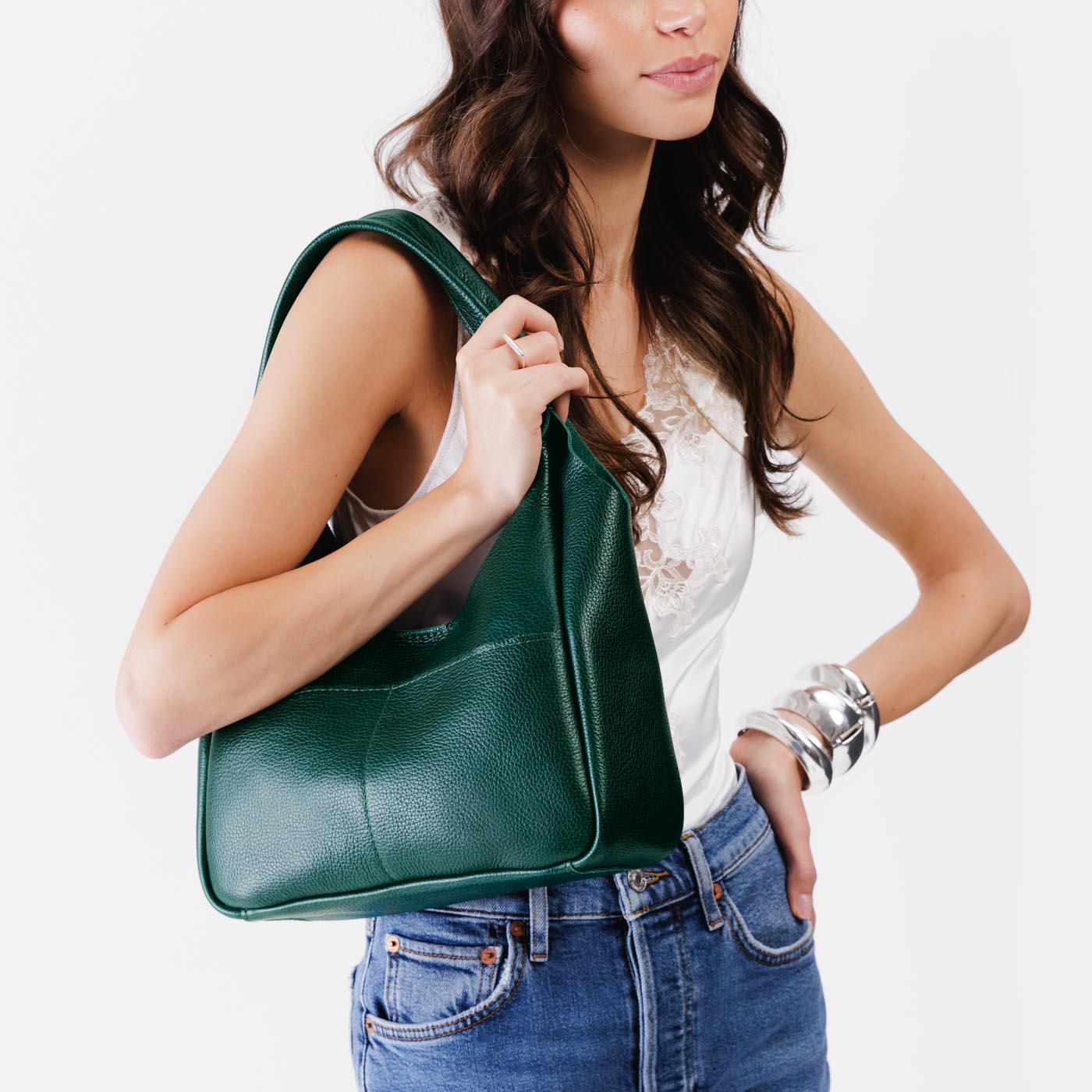 Forest Green*Medium | A model holding a u-shaped, flat-bottomed leather shoulder bag with two outside pockets