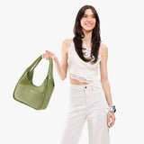 Laurel Medium | A model holding a u-shaped, flat-bottomed leather shoulder bag with two outside pockets