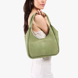Laurel Medium | A model holding a u-shaped, flat-bottomed leather shoulder bag with two outside pockets