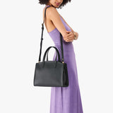 Black Medium | Model carrying leather tote bag with handles, adjustable crossbody strap, and two back pockets