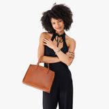 Honey Medium | Model carrying leather tote bag with handles, adjustable crossbody strap, and two back pockets