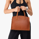 Honey Medium | Model carrying leather tote bag with handles, adjustable crossbody strap, and two back pockets
