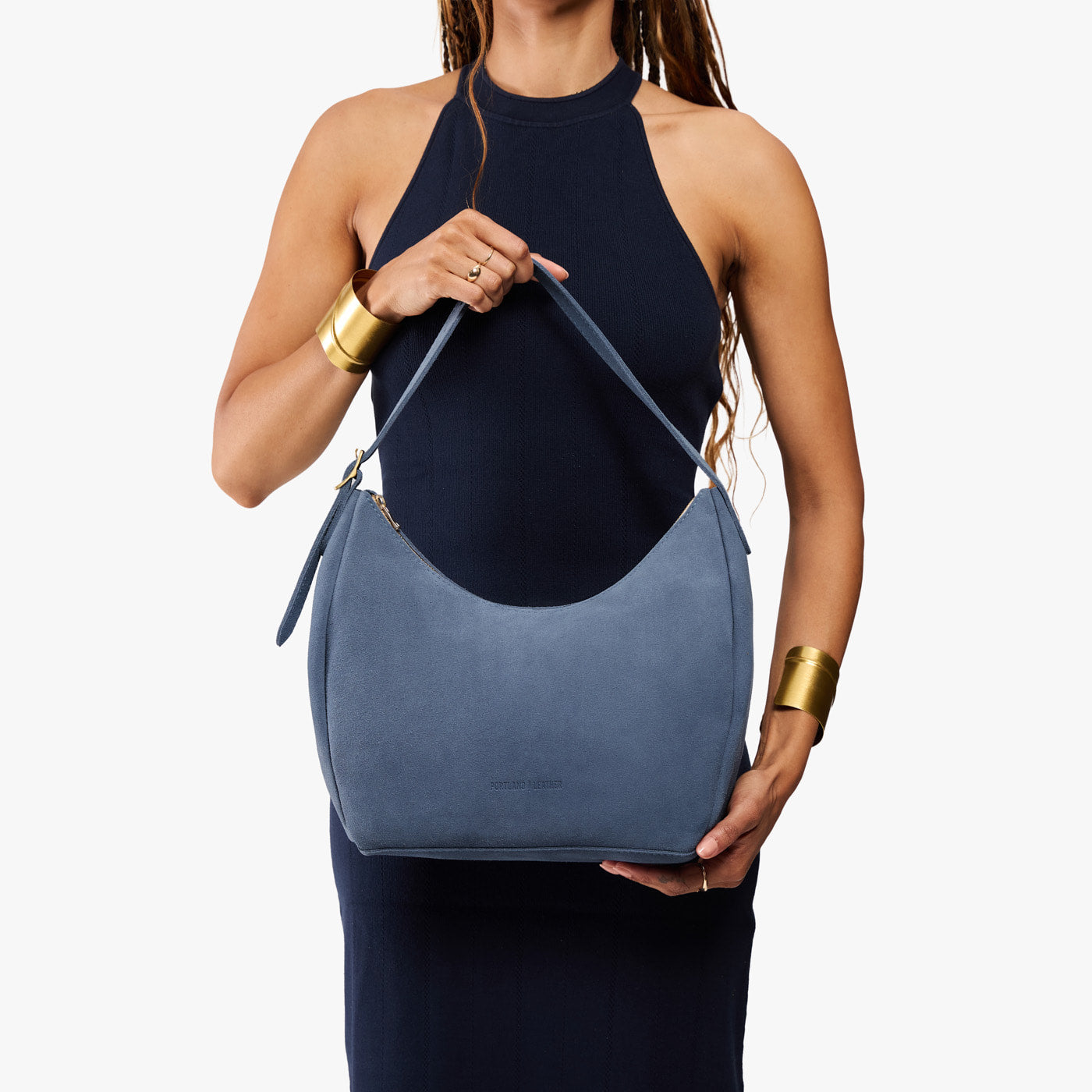 Denim*Medium | Model holding u-shaped, flat-bottomed leather shoulder bag with adjustable strap
