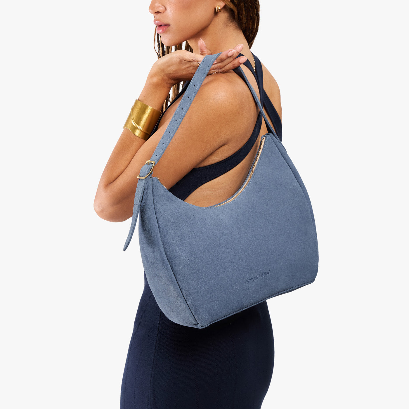 Denim*Medium | Model holding u-shaped, flat-bottomed leather shoulder bag with adjustable strap