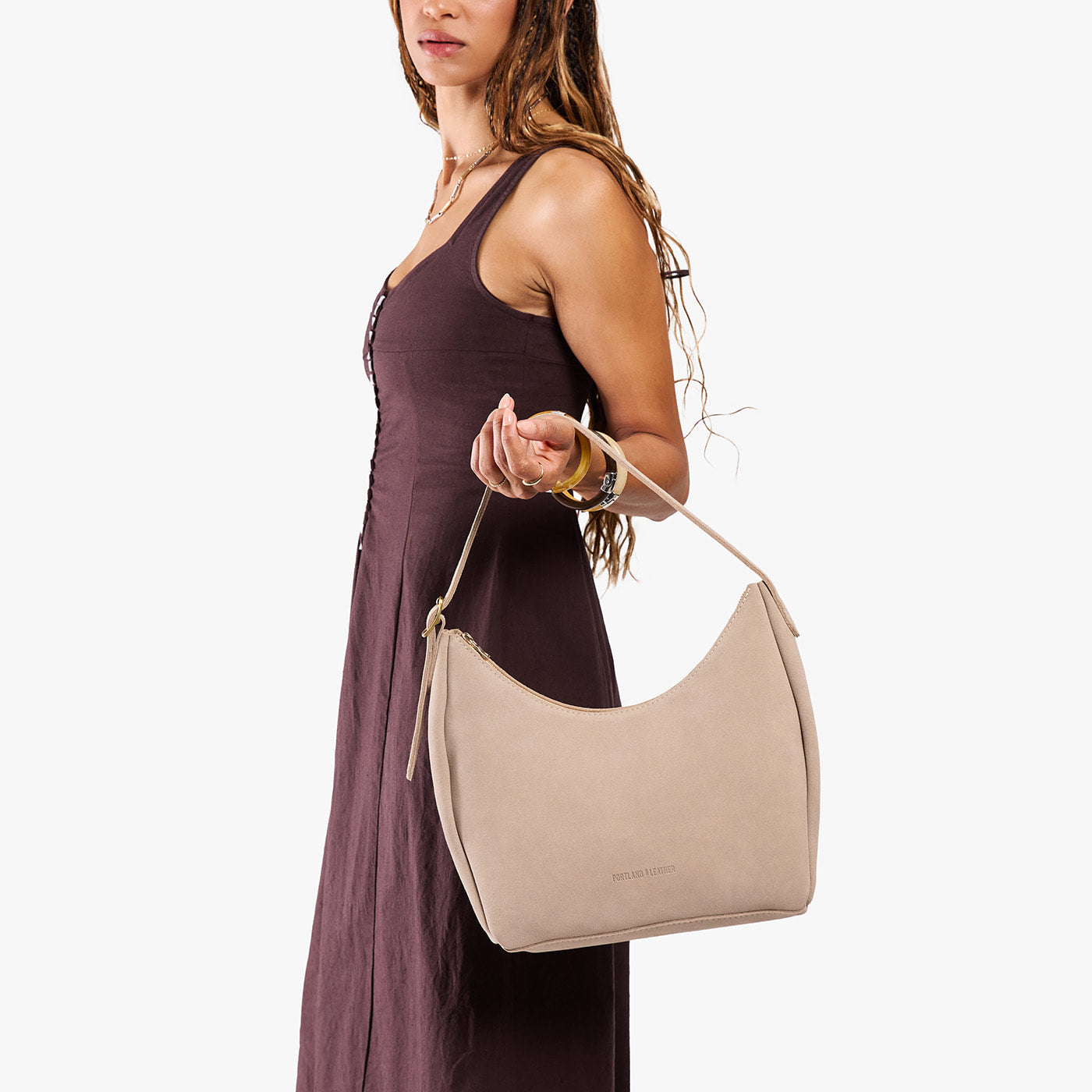Taupe*Medium | Model holding u-shaped, flat-bottomed leather shoulder bag with adjustable strap