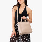 Oatmilk Classic | Model holding midsize crossbody tote with handles and a pocket