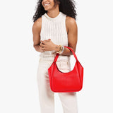 Candy Medium | Model carrying a u-shaped, flat-bottomed leather shoulder bag with two outside pockets