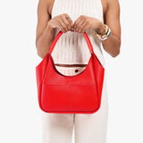 Candy Medium | Model holding a u-shaped, flat-bottomed leather shoulder bag with two outside pockets