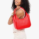 Candy Medium | Model holding a u-shaped, flat-bottomed leather shoulder bag with two outside pockets