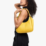 Pomello Medium | Model carrying a u-shaped, flat-bottomed leather shoulder bag with two outside pockets