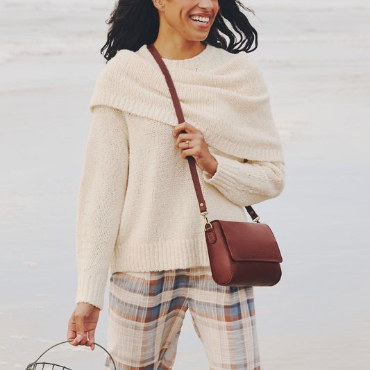 A model standing in the surf wearing a Metro crossbody bag.