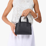 Black Mini | Model holding small leather tote bag with handles, adjustable crossbody strap, and one back pocket