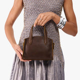 Coldbrew Mini | Model holding small leather tote bag with handles, adjustable crossbody strap, and one back pocket