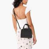 Full Moon Mini | Model carrying small leather tote bag with handles, adjustable crossbody strap, and one back pocket