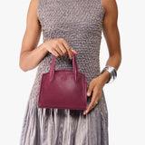 Orchid Mini | Model holding small leather tote bag with handles, adjustable crossbody strap, and one back pocket