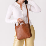 Meadow Classic | Model holding crossbody tote bag with snap closure and front pocket
