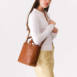 Meadow Classic | Model holding crossbody tote bag with snap closure and front pocket