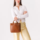 Meadow Classic | Model holding crossbody tote bag with snap closure and front pocket