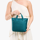 Aquarius Zipper | Model holding crossbody tote bag with zipper closure and front pocket