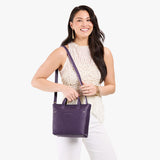 Empire Zipper | Model holding crossbody tote bag with zipper closure and front pocket