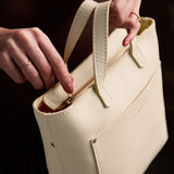 Pebbled Bone Zipper | Model carrying crossbody tote bag with snap closure and front pocket