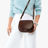 Chocolate Brown Small | Model wearing a petite leather Crossbody with a flap and magnetic closure