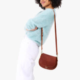 Nutmeg Small | Model wearing a petite leather Crossbody with a flap and magnetic closure
