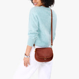 Nutmeg Small | Model wearing a petite leather Crossbody with a flap and magnetic closure