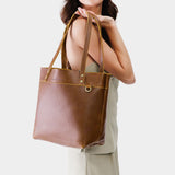 Asheville | Model holding a leather tote bag with riveted straps and exterior key loop