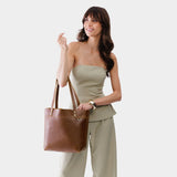 Asheville | Model holding a leather tote bag with riveted straps and exterior key loop