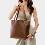 Asheville | Model holding a leather tote bag with riveted straps and exterior key loop