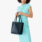 Boreal | Model holding leather tote bag with riveted straps and exterior key loop 