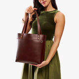 Cognac | Model wearing leather tote bag with riveted straps and exterior key loop