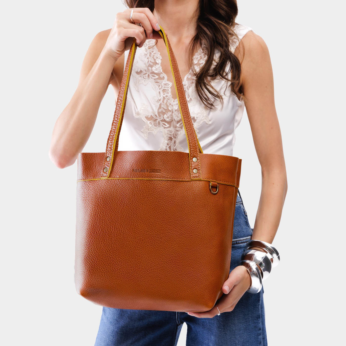 Sienna | Model holding a leather tote bag with riveted straps and exterior key loop