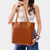Sienna | Model holding a leather tote bag with riveted straps and exterior key loop