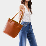 Sienna | Model holding a leather tote bag with riveted straps and exterior key loop