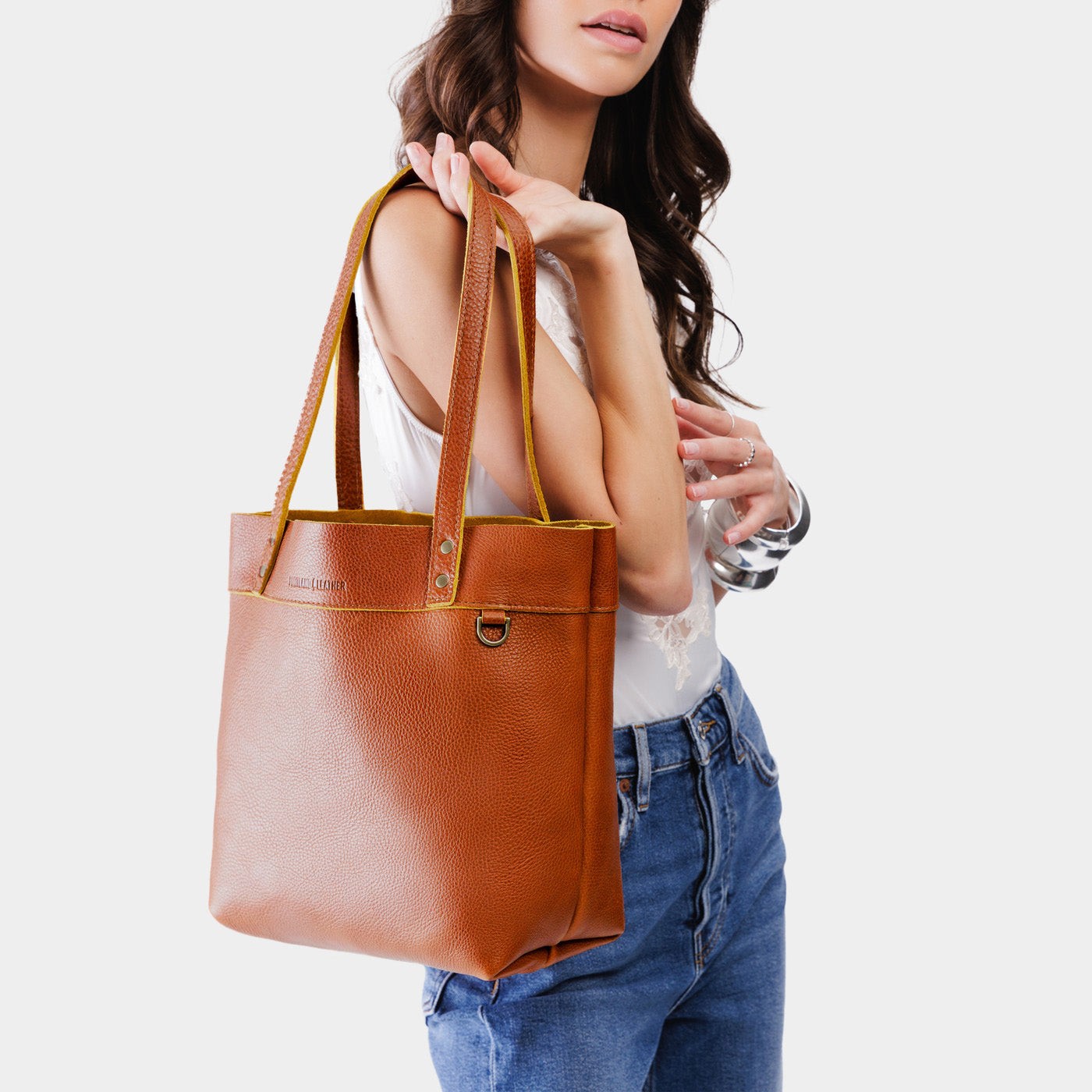 Sienna | Model holding a leather tote bag with riveted straps and exterior key loop