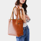 Sienna | Model holding a leather tote bag with riveted straps and exterior key loop