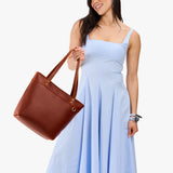 Nutmeg Medium Zipper | Model wearing leather tote bag with riveted straps and exterior key loop