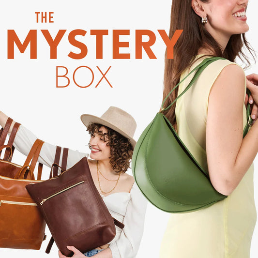 Promotional graphic for 'The Mystery Box' featuring three models holding various leather accessories, including a green crescent shoulder bag, a brown tote bag, and a brown backpack, set against a clean white background with bold orange text.