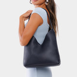 Night Owl Large | Model wearing mid-size shoulder bag with adjustable strap and magnetic snap closure