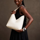 Pebbled Bone Large | Model holding mid-size shoulder bag with magnetic snap closure