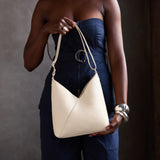 Pebbled Bone Small | Model holding petite shoulder bag with adjustable strap and magnetic snap closure