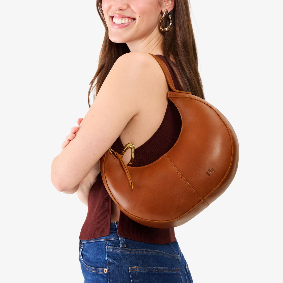 Honey*Small | Model carrying crescent shaped leather shoulder bag with zipper closure and adjustable strap