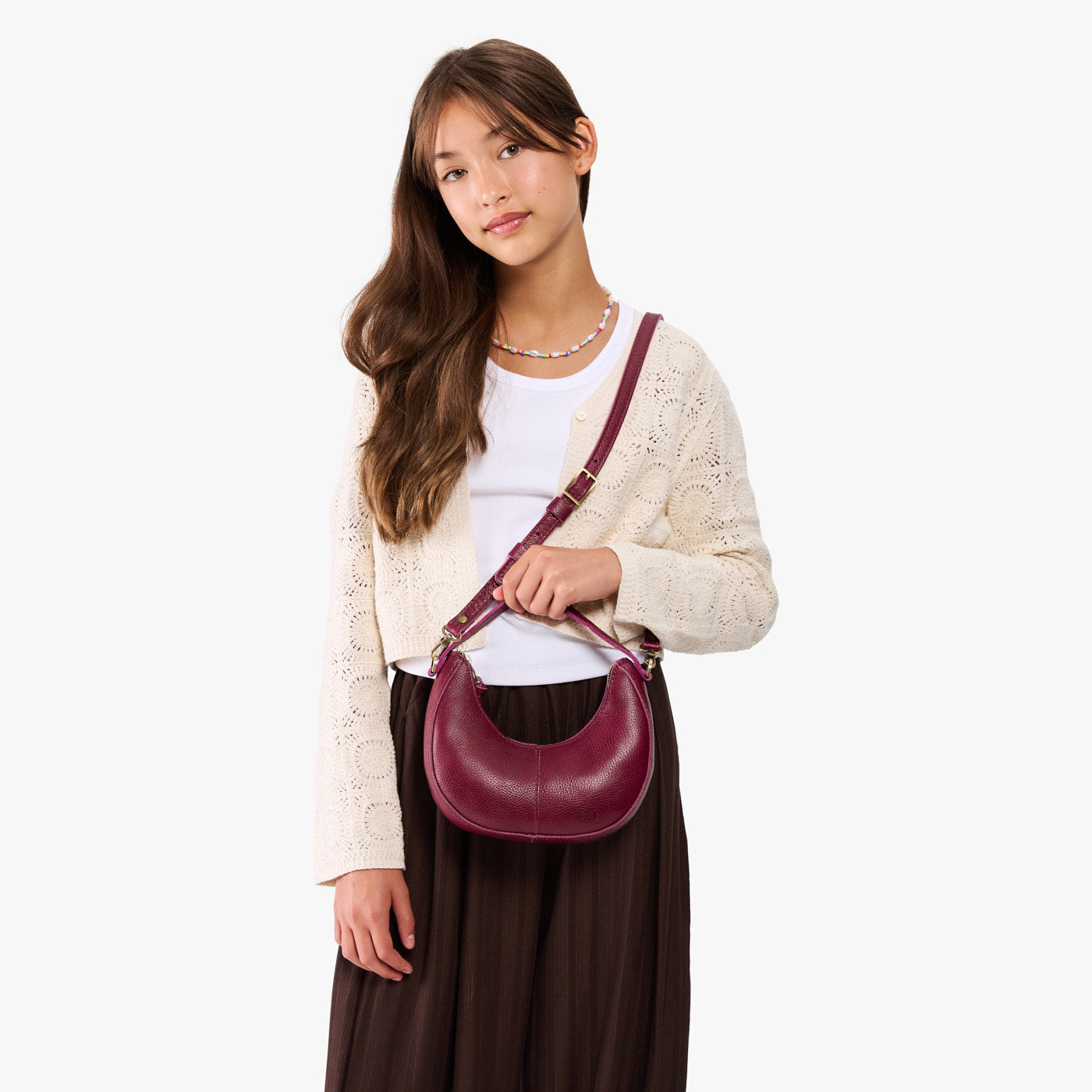 Orchid | Model with a crescent shaped shoulder bag with zipper closure and gold accents