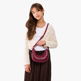 Orchid | Model with a crescent shaped shoulder bag with zipper closure and gold accents